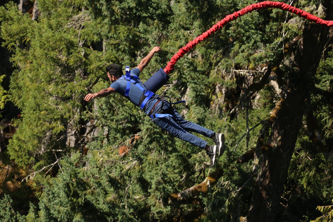 vision A man experiences the thrill of bungee jumping over a forest, showcasing adventure and excitement.