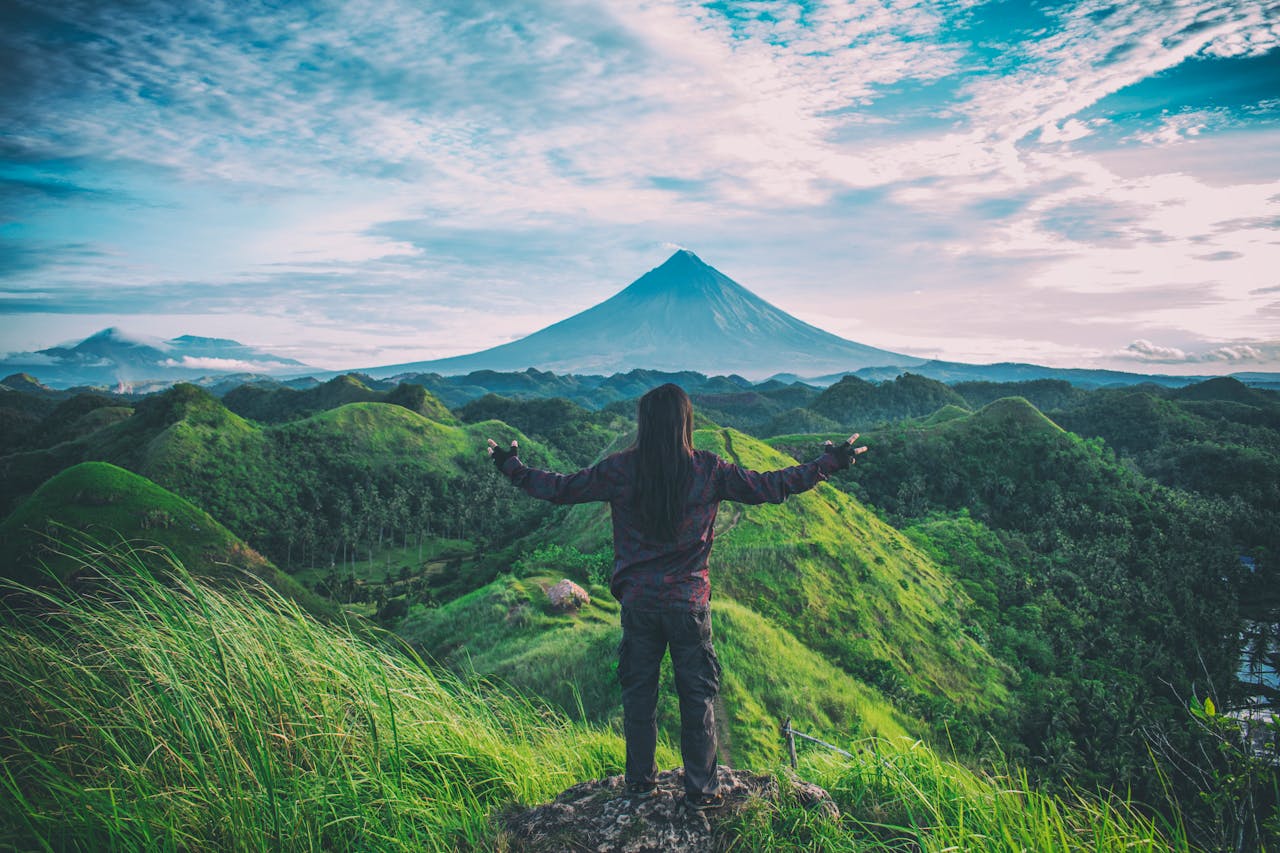 gallery-01 A person enjoys an expansive view of Mt. Mayon amidst lush green hills in Bicol, Philippines.